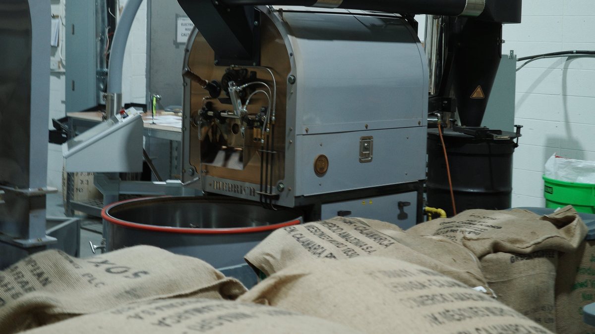 The Ridgeline roaster with burlap sacks of green coffee beans