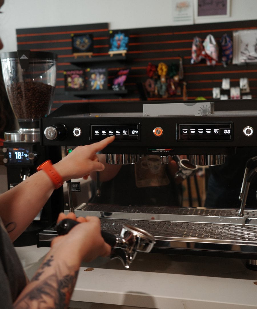 Dialling in an espresso machine at a client's bar while a barista holds the portafilter